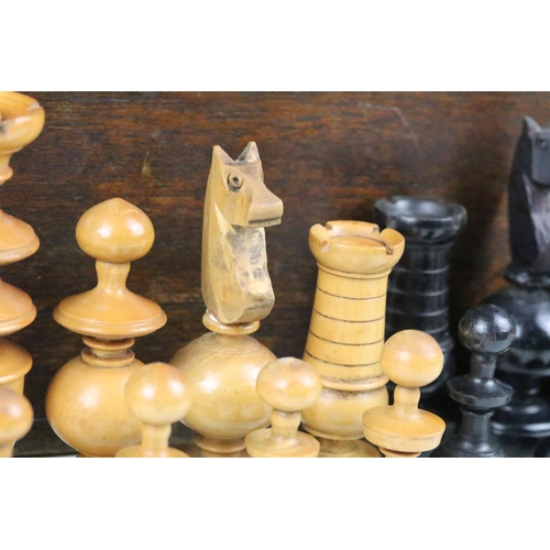 267 - A turned wooden chess set within an antique wooden box, queen stands approx 9cm in height.