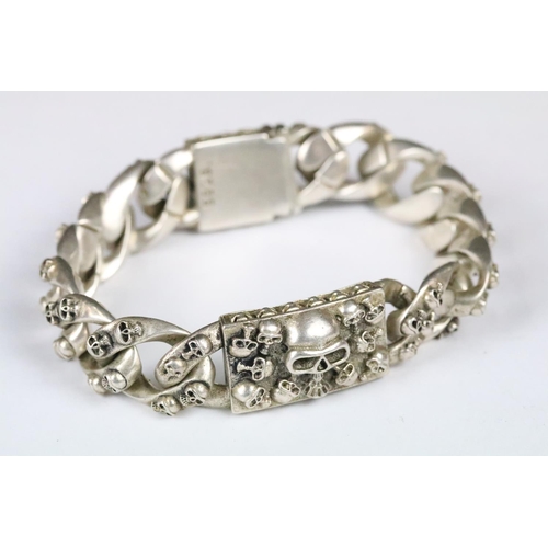 203 - A white metal heavy weight skull bracelet, curb linked with skull detail to each link, centre panel ... 