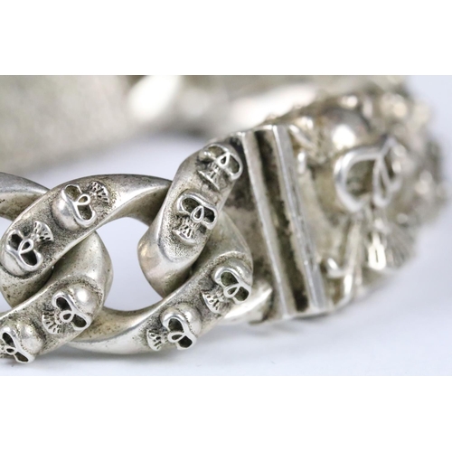 203 - A white metal heavy weight skull bracelet, curb linked with skull detail to each link, centre panel ... 