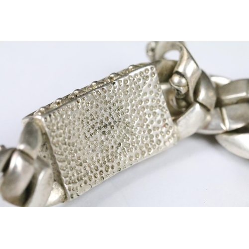 203 - A white metal heavy weight skull bracelet, curb linked with skull detail to each link, centre panel ... 