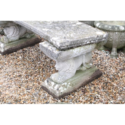 528 - Reconstituted stone garden bench with curved seat raised upon lion supports (matched), approx 175cm ... 