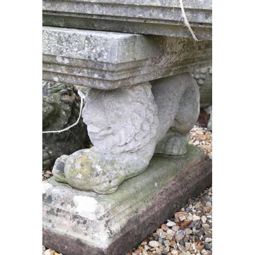 528 - Reconstituted stone garden bench with curved seat raised upon lion supports (matched), approx 175cm ... 