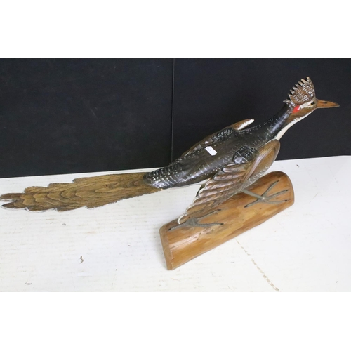 150 - Carved wooden bird sculpture having hand painted details raised on a naturalistic wooden base. Measu... 