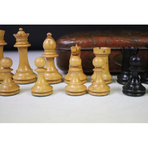 180 - A set of early 20th century boxwood chess pieces within a Huntley & Palmers biscuit tin.