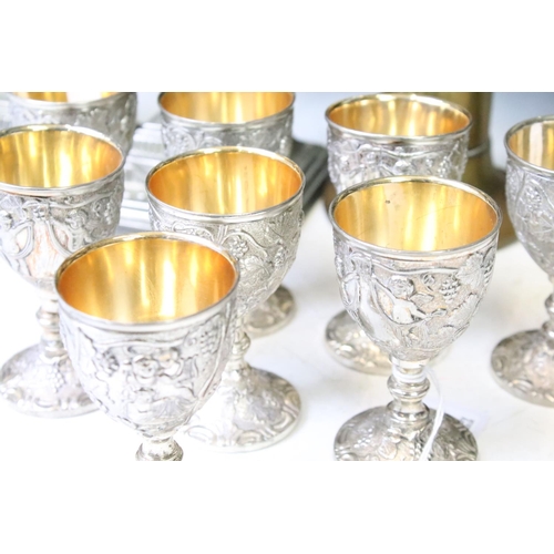 342 - Set of eight white metal drinking vessels with cast grape & vine decoration and gilt interiors (appr... 