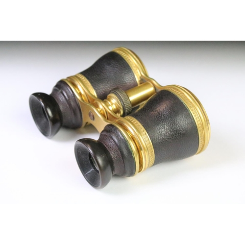 28 - A pair of mid 20th century leather clad binoculars with decorative gilt decoration housed within a s... 