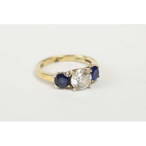 242 - A silver gilt ladies dress ring with clear centre stone and blue stones set to either side.