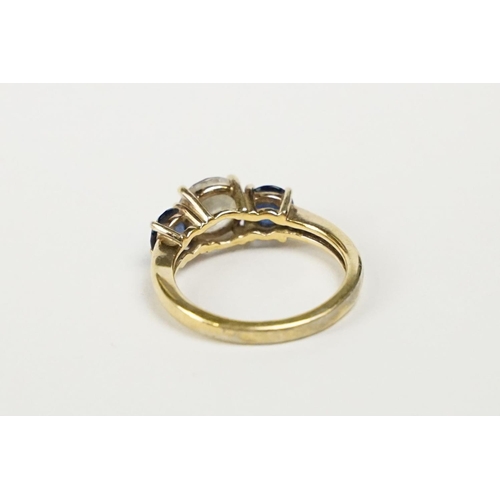 242 - A silver gilt ladies dress ring with clear centre stone and blue stones set to either side.