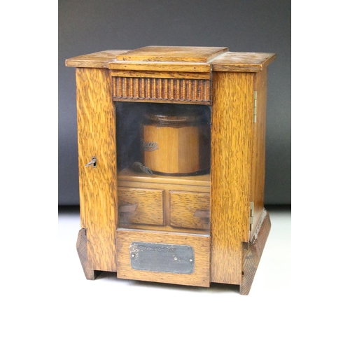 194 - Art Deco oak smokers cabinet, the glazed door opening to a tobacco pipe racks & tobacco jar above tw... 