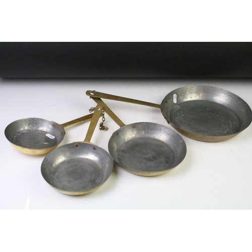 200 - Graduating set of four brass frying pans (largest diameter approx 23cm), together with a brass hand ... 