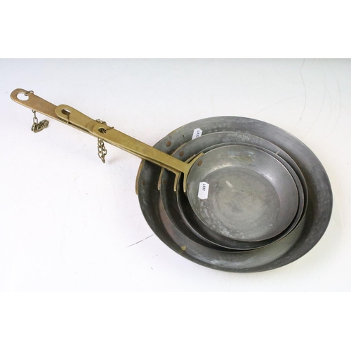 200 - Graduating set of four brass frying pans (largest diameter approx 23cm), together with a brass hand ... 