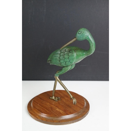 143 - Bronze figure of a green bird, possibly a crane, raised on a circular wooden plinth (approx 22.5cm h... 