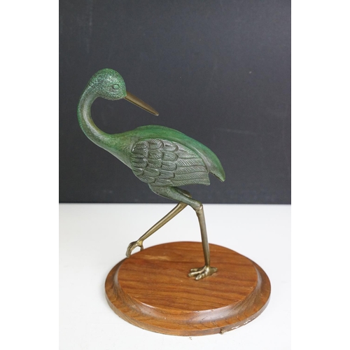 143 - Bronze figure of a green bird, possibly a crane, raised on a circular wooden plinth (approx 22.5cm h... 