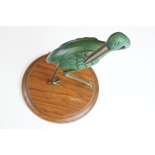 143 - Bronze figure of a green bird, possibly a crane, raised on a circular wooden plinth (approx 22.5cm h... 