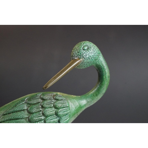 143 - Bronze figure of a green bird, possibly a crane, raised on a circular wooden plinth (approx 22.5cm h... 