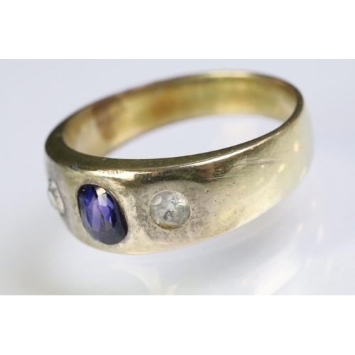 241 - Yellow metal three stone ring set with a cushion cut purple stone to the centre flanked by two round... 