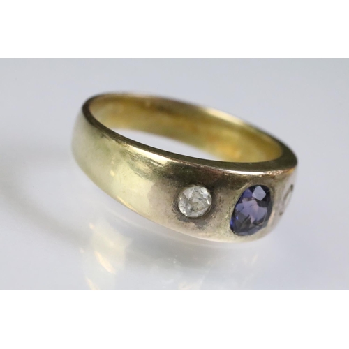 241 - Yellow metal three stone ring set with a cushion cut purple stone to the centre flanked by two round... 