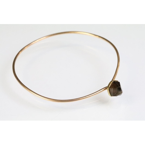 248 - Rose gold bangle bracelet having a hook clasp set with a smokey quartz crystal. Unmarked, assessed a... 