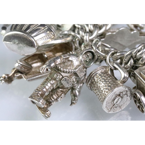 203 - Silver charm bracelet having a curb link chain with a dog lead clasp, mounted with approximately 34 ... 