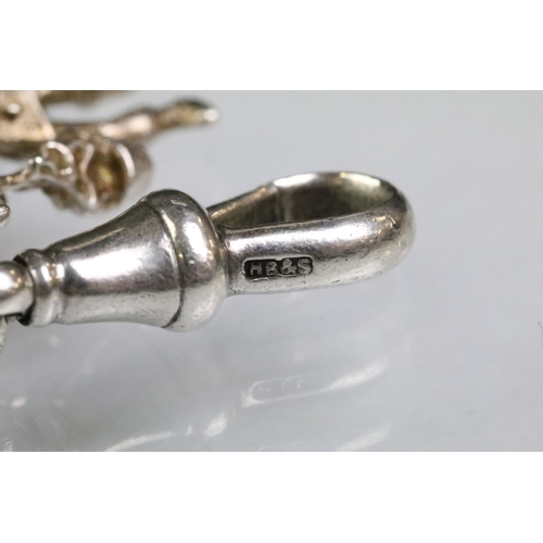 203 - Silver charm bracelet having a curb link chain with a dog lead clasp, mounted with approximately 34 ... 