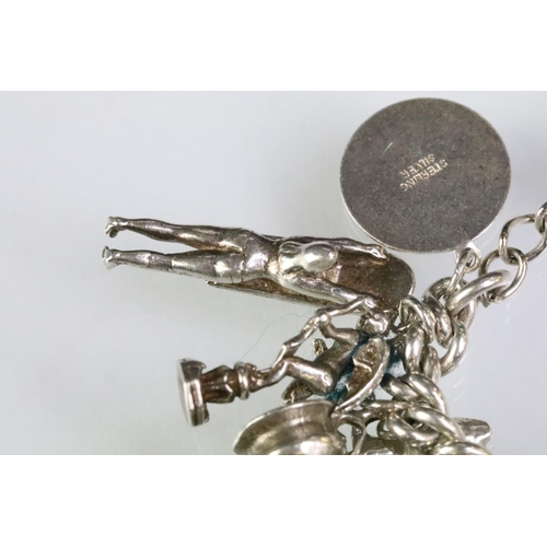 203 - Silver charm bracelet having a curb link chain with a dog lead clasp, mounted with approximately 34 ... 