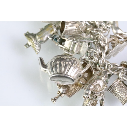 203 - Silver charm bracelet having a curb link chain with a dog lead clasp, mounted with approximately 34 ... 