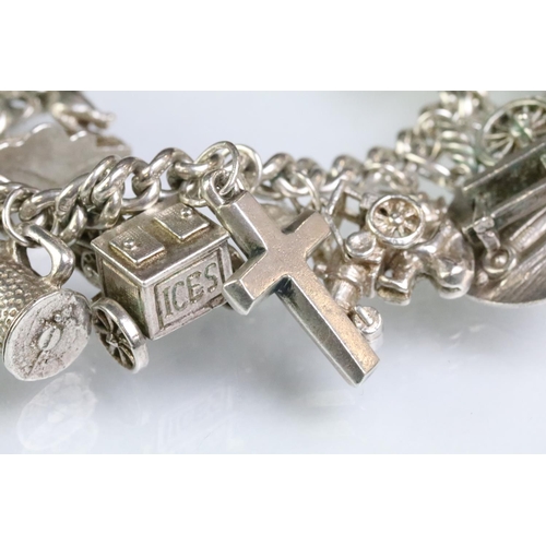 203 - Silver charm bracelet having a curb link chain with a dog lead clasp, mounted with approximately 34 ... 