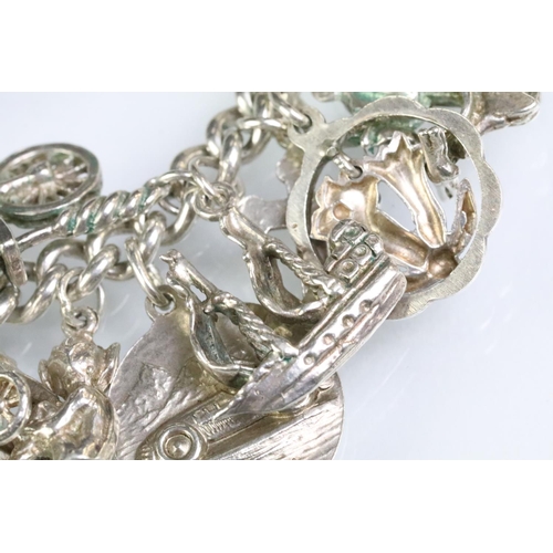 203 - Silver charm bracelet having a curb link chain with a dog lead clasp, mounted with approximately 34 ... 