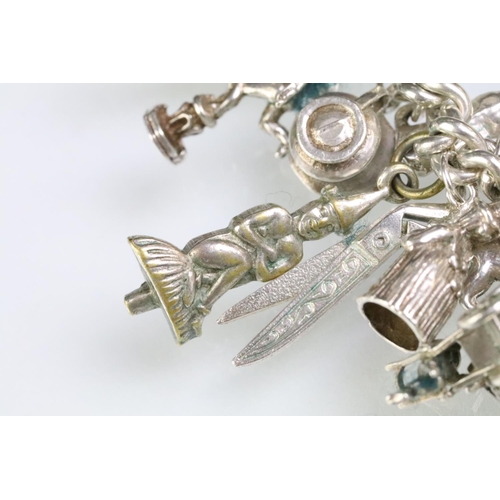 203 - Silver charm bracelet having a curb link chain with a dog lead clasp, mounted with approximately 34 ... 