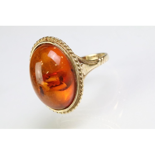 214 - 9ct gold hallmarked amber ring being set with an oval amber cabochon in a rub over setting. Hallmark... 