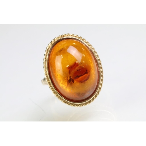 214 - 9ct gold hallmarked amber ring being set with an oval amber cabochon in a rub over setting. Hallmark... 