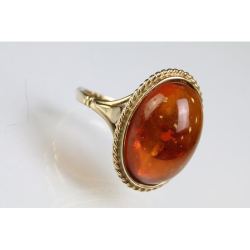 214 - 9ct gold hallmarked amber ring being set with an oval amber cabochon in a rub over setting. Hallmark... 