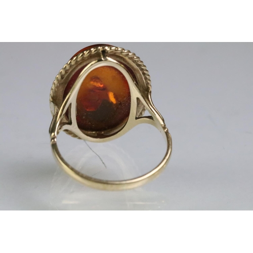 214 - 9ct gold hallmarked amber ring being set with an oval amber cabochon in a rub over setting. Hallmark... 