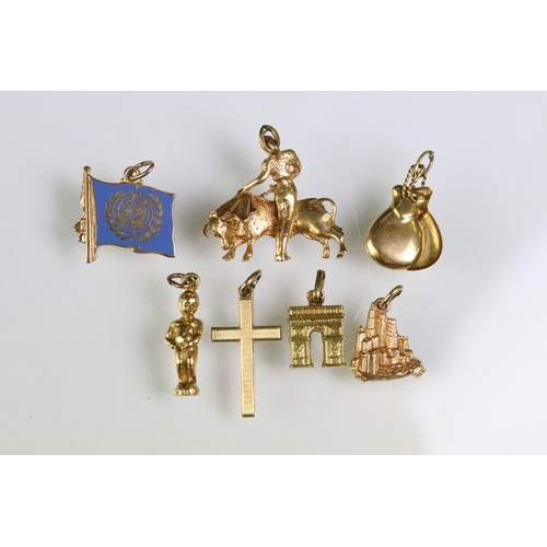 215 - Collection of gold charms to include a 9ct gold hallmarked cross, 14ct gold enamelled flag charm (ma... 