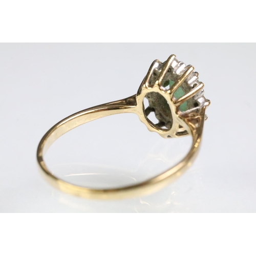 216 - 9ct gold hallmarked emerald and diamond cluster ring. The ring being set with an oval cut emerald su... 