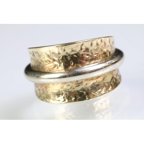 224 - 9ct gold two tone ring having a wide textured band with white gold ring to centre. Marked 375. Size ... 