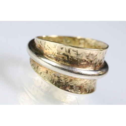 224 - 9ct gold two tone ring having a wide textured band with white gold ring to centre. Marked 375. Size ... 