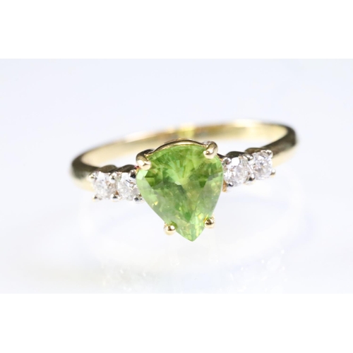 296 - 18ct gold sphene and diamond ring. The ring being set with a pear cut peridot to centre flanked by t... 