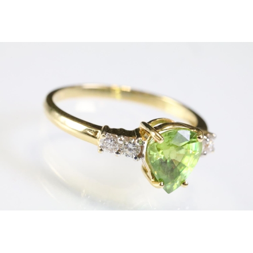 296 - 18ct gold sphene and diamond ring. The ring being set with a pear cut peridot to centre flanked by t... 