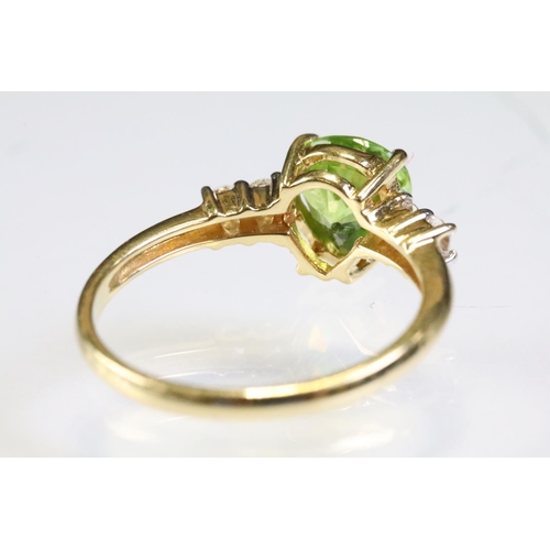 296 - 18ct gold sphene and diamond ring. The ring being set with a pear cut peridot to centre flanked by t... 