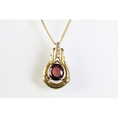 309 - 9ct gold and ruby pendant being set with an oval cut ruby within a gold mount with accent stones to ... 