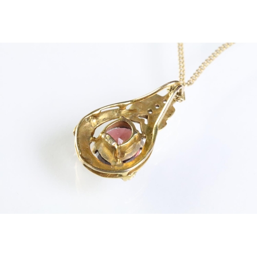 309 - 9ct gold and ruby pendant being set with an oval cut ruby within a gold mount with accent stones to ... 