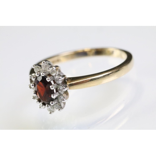 317 - 9ct gold hallmarked garnet and diamond cluster ring being set with an oval cut garnet to centre with... 