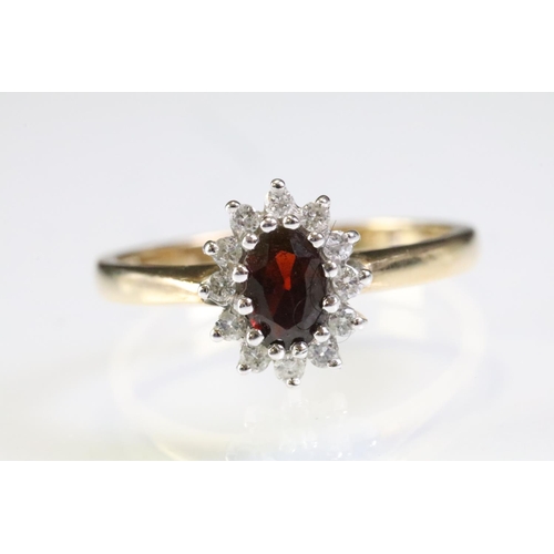 317 - 9ct gold hallmarked garnet and diamond cluster ring being set with an oval cut garnet to centre with... 