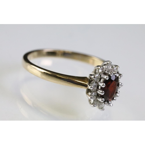 317 - 9ct gold hallmarked garnet and diamond cluster ring being set with an oval cut garnet to centre with... 