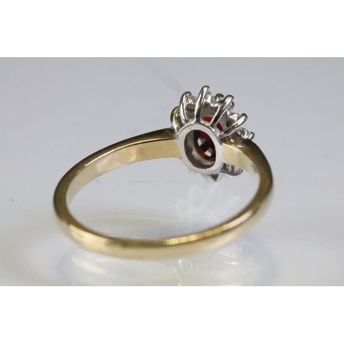 317 - 9ct gold hallmarked garnet and diamond cluster ring being set with an oval cut garnet to centre with... 