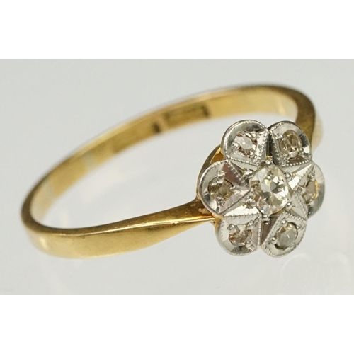 101 - 1920s 18ct gold, platinum and diamond daisy head ring being set with seven round cut diamonds on tap... 