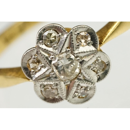 101 - 1920s 18ct gold, platinum and diamond daisy head ring being set with seven round cut diamonds on tap... 