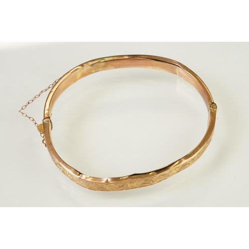 124 - 9ct gold hallmarked hinged bangle bracelet. The bracelet having incised scrolled foliate detailing, ... 