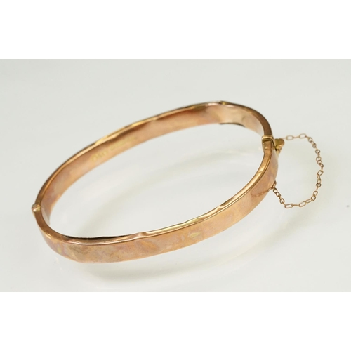 124 - 9ct gold hallmarked hinged bangle bracelet. The bracelet having incised scrolled foliate detailing, ... 